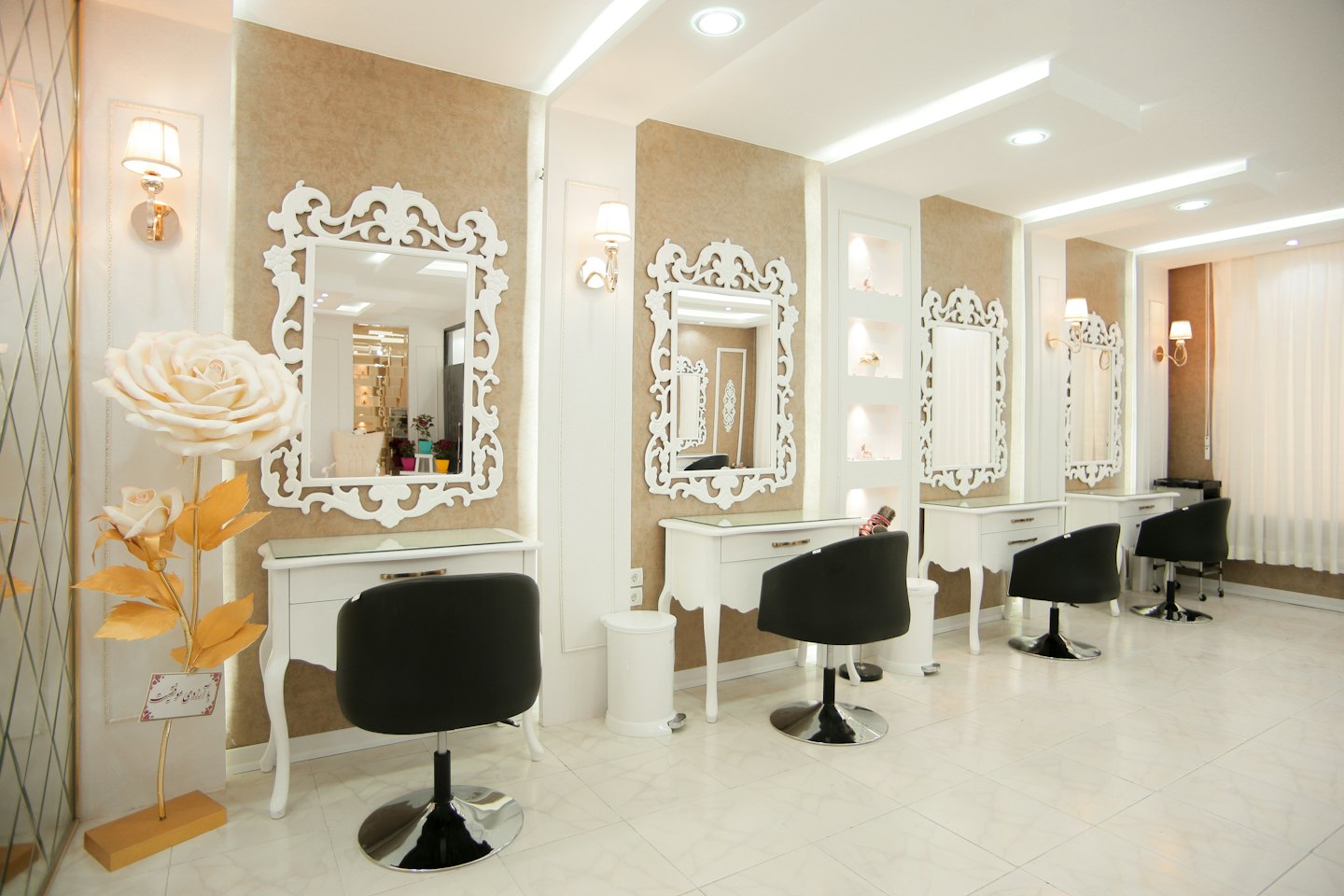 Moderne schoonheidssalon met stylingstations en decoratieve rozensculptuur.